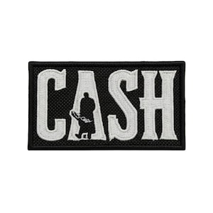 May include: A rectangular embroidered patch with a black background and a white border. The word CASH is stitched in large white block letters, with a black silhouette of a person standing inside the letter A, holding a guitar.