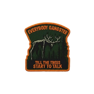 Op de afbeelding: Een rechthoekige geborduurde patch met een oranje rand en een donkergroene bosachtergrond. Het toont het witte silhouet van een skelet-hert en de oranje tekst "EVERYBODY GANGSTER TILL THE TREES START TO TALK" in een vetgedrukt lettertype.