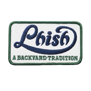 May include: A rectangular embroidered patch with a white background and a dark green border. The patch features the word Phish in dark blue cursive embroidery, with the text A BACKYARD TRADITION stitched in dark green capital letters below it.
