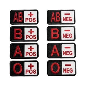 May include: A set of eight rectangular embroidered patches featuring blood types. Each patch has a black background with a large red letter and a white section containing a red plus or minus sign with the text POS or NEG in red lettering.
