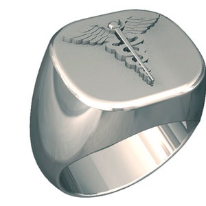 Może przedstawiać: Srebrny pierścień z kwadratową górą z wytłoczonym symbolem kaduceusza. Pierścień ma polerowaną, odblaskową powierzchnię i zaokrągloną obręcz. Symbol kaduceusza zawiera laskę, dwa węże i skrzydła.