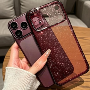 May include: A deep burgundy smartphone case featuring a glittery finish and a clear back panel. The case has a metallic-toned frame, precise cutouts for the camera lenses, and a smooth, matte-textured section on the lower portion of the back.