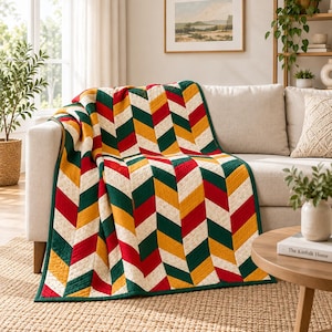 May include: A quilted throw blanket featuring a repeating chevron pattern in alternating stripes of dark green, mustard yellow, red, and a cream-colored fabric with a subtle floral print, finished with a solid dark green fabric border.