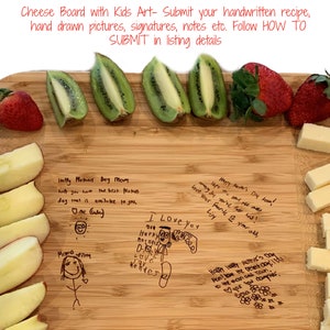 May include: A wooden cutting board with a variety of fruits and cheese arranged on it. The board is decorated with handwritten messages and drawings from children. The messages include "Happy Mother's Day Mom" and "I Love You".