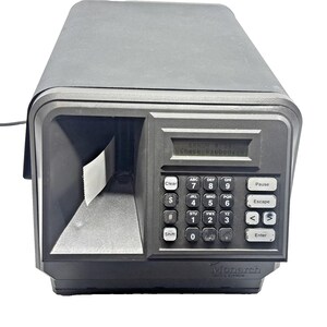 May include: A black Monarch label printer featuring a digital display screen showing the text ERROR #734 Check Ribbon. The device includes a numeric keypad with function buttons and a paper output slot containing a white strip of label material.