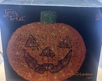 May include: An orange pumpkin-shaped Jack-O-Lantern light with a green stem, featuring black mesh eyes, nose, and mouth. The product is displayed in a black box labeled Trick or Treat and Jack-O-Lantern Light, with a UL Listed certification mark.