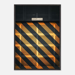 Könnte beinhalten: Ein gerahmter Kunstdruck, der ein Garagentor mit schwarzen und gelben diagonalen Warnstreifen zeigt. Ein kleines rechteckiges Schild oben in der Mitte zeigt den Text HOOGTE 2.10 M. Das Tor hat eine gitterartige Textur und einen dunklen Rahmen.