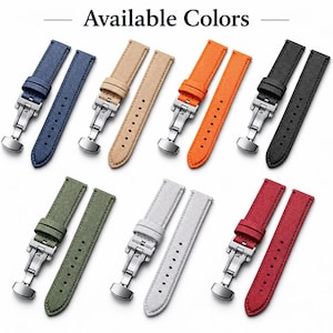 May include: A collection of watch straps in navy blue, beige, orange, black, olive green, light grey, and red. Each strap features a textured fabric surface, a silver-toned metal deployment clasp, and a series of adjustment holes. Text reads Available Colors.