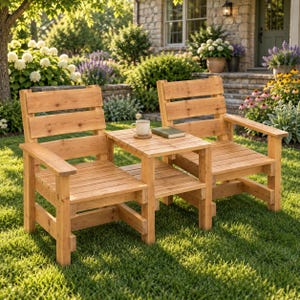 Op de afbeelding: Een tuinmeubelset van natuurlijk hout bestaande uit twee stoelen verbonden door een centrale vierkante tafel. De stoelen hebben horizontale latten op de rugleuningen en zittingen, met platte armleuningen. Een witte mok staat op de tafel naast een gesloten boek.
