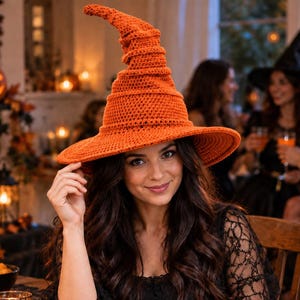 May include: A bright orange crocheted witch hat with a tall, pointed, and slightly slouchy crown and a wide, circular brim. The hat features a textured, hand-stitched yarn construction with a consistent stitch pattern throughout the entire piece.