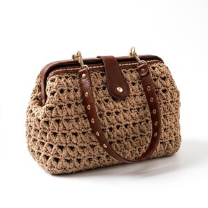 Könnte beinhalten: Eine beige gehäkelte Handtasche mit einem strukturierten Rahmen aus dunkelbraunem Leder und einem passenden Ledergriff. Die Tasche hat einen zentralen Lederverschluss mit einem goldenen Druckknopf und goldfarbenen Beschlägen.