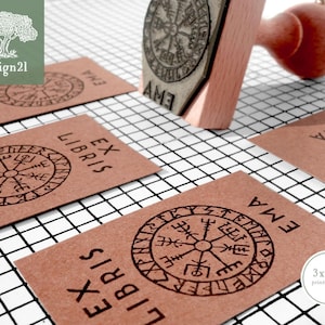 May include: A set of four brown cards with the text "Ex Libris" and a black compass design. The cards are on a white grid background. A wooden stamp with a black compass design is also shown. The stamp is 3 cm by 5 cm.