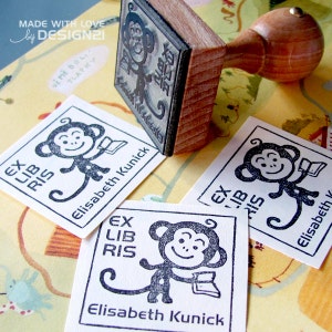 May include: Three white square stamps with black ink showing a monkey holding a book. The text on the stamps reads "Ex Libris" and "Elisabeth Kunick".