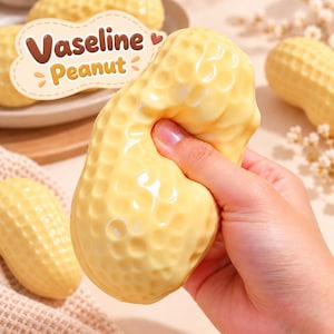 Könnte beinhalten: Ein blassgelbes, erdnussförmiges Quetschspielzeug mit einer texturierten, genoppten Oberfläche. Ein grafisches Etikett in der oberen linken Ecke zeigt ein braunes Herzsymbol und den Text Vaseline Peanut in brauner und gelber Schrift.