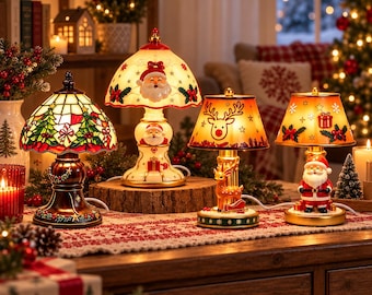 Könnte beinhalten: Vier dekorative Weihnachtstischlampen mit festlichen Motiven. Eine Lampe hat einen Lampenschirm im Buntglas-Stil mit Tannenbäumen, während die anderen Weihnachtsmann- und Rentier-Motive auf cremefarbenen und orangefarbenen Schirmen zeigen.