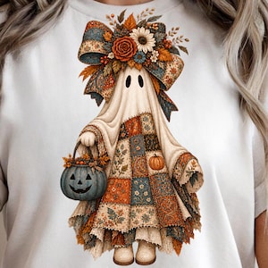 Może przedstawiać: Biały t-shirt z grafiką ducha noszącego dużą kwiatową kokardę i sukienkę patchworkową w odcieniach pomarańczu, błękitu i kremu. Duch trzyma niebieskie wiaderko w kształcie dyni wypełnione jesiennymi liśćmi oraz małymi dyniami.
