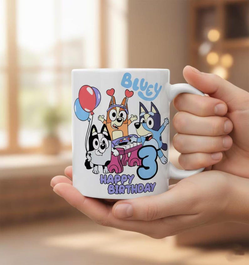 Pode incluir: Uma caneca de cer&acirc;mica branca com um gr&aacute;fico colorido das personagens de desenhos animados Bluey e Bingo. O design inclui o texto Bluey, Happy Birthday e um n&uacute;mero 3 grande em azul, juntamente com bal&otilde;es e um piano cor-de-rosa.