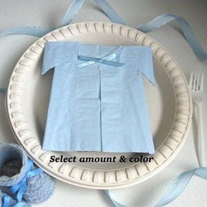 May include: A white paper plate with a blue napkin folded into the shape of a shirt. The napkin has a blue ribbon tied around the neck. The plate is surrounded by blue ribbon.