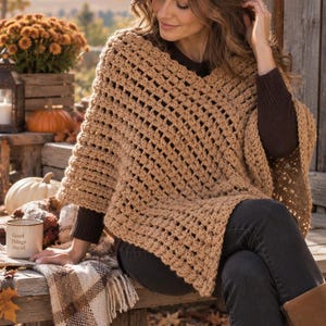 May include: A tan crochet poncho featuring a V-neckline and an open-weave granny square pattern. The garment is worn over a dark brown long-sleeve shirt, dark pants, and brown boots. A white mug with the text Good Things Ahead is visible.