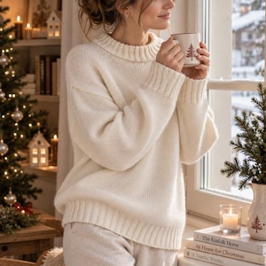 Peut inclure: Un pull en tricot épais blanc cassé à manches longues avec un col rond, des poignets et un ourlet côtelés. Le pull présente un tissage texturé et une coupe décontractée, associé à un pantalon blanc cassé assorti pour une tenue coordonnée.