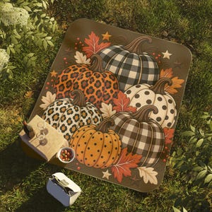 May include: A square blanket featuring a pattern of pumpkins with various designs including black and white buffalo plaid, leopard print, and polka dots, accented with orange and cream autumn leaves, small stars, and red berries on a brown background.
