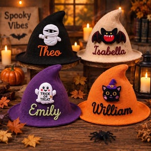 May include: Four knitted witch hats in black, beige, purple, and orange. The black hat features a mummy and the name Theo. The beige hat has a bat and the name Isabella. The purple hat shows a ghost with Trick or Treat and the name Emily. The orange hat displays a cat and the name William.