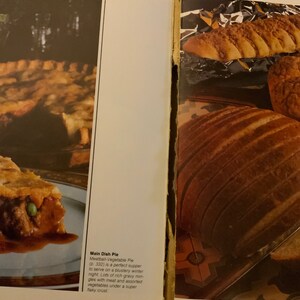 May include: A close-up of a meatball and vegetable pie with a flaky crust. The pie is on a blue and white plate. The text "Main Dish Pie Meatball-Vegetable Pie (p. 332) is a perfect supper to serve on a blustery winter night. Lots of rich gravy mingles with meat and assorted vegetables under a super flaky crust." is visible in the image.