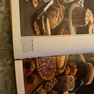 May include: A variety of baked goods, including a coffee cake, muffins, a chocolate cake, a braided loaf, and cookies. The baked goods are arranged on a table with a checkered tablecloth.