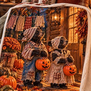 May include: A plush fleece blanket featuring a printed scene of two bear cubs dressed in rustic clothing, each holding a jack-o'-lantern candy bucket. The cubs stand on a wooden porch surrounded by pumpkins, autumn leaves, and a cabin door.