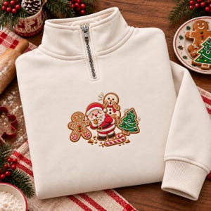 Puede incluir: Una sudadera color crema con cremallera corta y un diseño bordado del Papá Noel rodeado por un hombre de jengibre, un muñeco de nieve, un árbol de Navidad y un bastón de caramelo en tonos rojos, verdes y marrones.