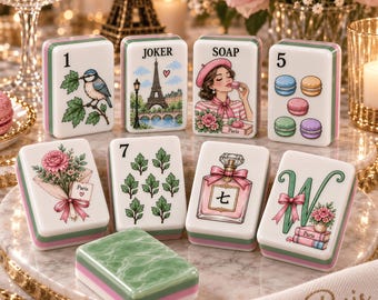 May include: A set of rectangular mahjong tiles featuring various illustrations including a bird, the Eiffel Tower with the text JOKER, a person with the text SOAP, macarons, a bouquet, the number 7, a perfume bottle, and the letter W.