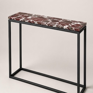 May include: A rectangular console table featuring a polished, deep red and white marble top with a distinct brecciated pattern. The tabletop is supported by a slender, open-frame base constructed from matte black metal tubing.