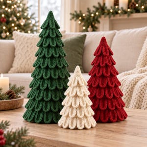 May include: Three cone-shaped decorative trees made of knit fabric. The tallest tree is dark green, the medium tree is red, and the smallest tree is cream-colored. Each tree features a textured, layered loop pattern resembling pine needles.