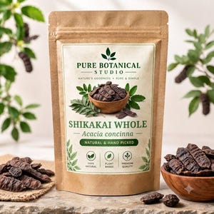 Op de afbeelding: Een bruine kraftpapieren zak met Shikakai Whole Acacia concinna van Pure Botanical Studio. Het etiket toont een houten kom met donkerbruine gedroogde zaaddozen, groene bladeren en tekst zoals 100% Natural, Plant Based, Premium Quality.