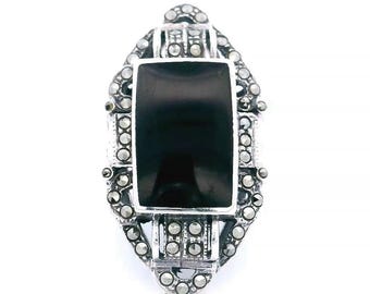 May include: A silver ring with a black onyx stone set in a geometric design. The ring is decorated with marcasite stones.