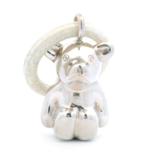 May include: A silver-toned pendant shaped like a seated bear, featuring a smooth, reflective surface. The bear is suspended from a textured, off-white circular ring that serves as a bail, creating a contrast between the metallic and matte finishes.