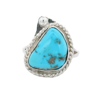 May include: A sterling silver ring featuring a teardrop-shaped turquoise stone with dark matrix inclusions. The stone is set in a smooth bezel surrounded by a twisted rope border, with a small silver bead accent at the top of the setting.