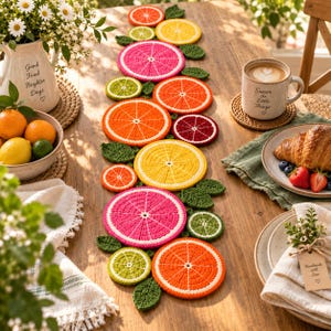 Puede incluir: Un camino de mesa de ganchillo que presenta una serie de coloridas rodajas de cítricos, incluyendo naranjas, limones, limas y pomelos en tonos rosa, naranja, amarillo y verde, intercaladas con pequeñas hojas de ganchillo verdes en línea.