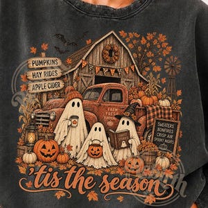Può includere: Una felpa girocollo grigio antracite con una stampa grafica di tre fantasmi davanti a un fienile rustico e un camion vintage. Il design include zucche, foglie autunnali e il testo PUMPKINS, HAY RIDES, APPLE CIDER e 'tis the season.