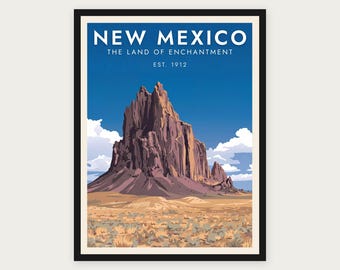 Puede incluir: Un póster de viaje enmarcado que muestra una gran formación rocosa marrón y dentada bajo un cielo azul intenso. El texto dice NEW MEXICO, THE LAND OF ENCHANTMENT, EST. 1912. El primer plano muestra un paisaje desértico con tierra.