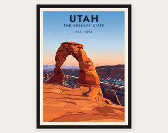 Puede incluir: Un póster enmarcado con una ilustración estilizada del arco naranja Delicate Arch en Utah. El texto dice UTAH, THE BEEHIVE STATE, EST. 1896. El fondo muestra un cielo con degradado sobre montañas lejanas y un paisaje rocoso.