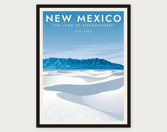 Puede incluir: Un póster de viaje enmarcado que muestra un paisaje de dunas de arena blanca bajo un cielo azul con montañas azules a lo lejos. El texto NEW MEXICO THE LAND OF ENCHANTMENT EST. 1912 aparece en letras mayúsculas blancas sobre el cielo.
