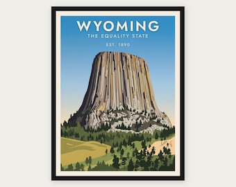 Puede incluir: Un póster de viaje enmarcado que muestra la Devils Tower en Wyoming. El texto dice WYOMING THE EQUALITY STATE EST. 1890. La imagen representa la alta formación rocosa columnar que se eleva sobre un bosque de pinos verdes y colinas.