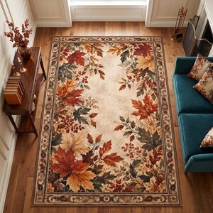 May include: A rectangular area rug featuring a central cream-colored field decorated with a border of autumn leaves in shades of red, orange, yellow, and dark green, accented by clusters of small berries and a dark brown patterned outer border.