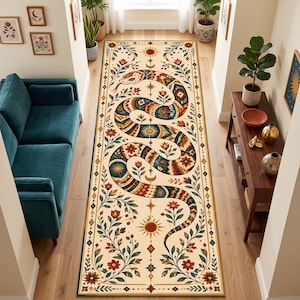 Könnte beinhalten: Ein langer, rechteckiger Läufer mit cremefarbenem Hintergrund und einem großen, gewundenen Schlangenmuster in Blaugrün, Orange und Braun. Das Design umfasst florale Motive, Sonnen- und Mondsymbole sowie geometrische Bordüren in symmetrischer Anordnung.