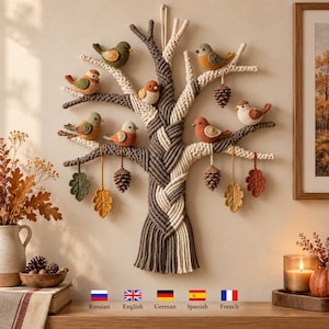 Puede incluir: Un tapiz de macramé con forma de árbol y ramas de cuerda trenzada en marrón y crema. El árbol presenta ocho pájaros de ganchillo de varios colores posados en las ramas, junto con piñas y hojas de colores otoñales tejidas a ganchillo.