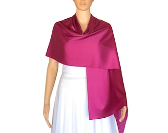 May include: A fuchsia pink satin shawl draped over a white dress. The shawl is long and flowing, with a soft, luxurious feel.
