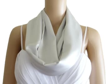 May include: A silver satin scarf, worn as a cowl neck, is draped around a mannequin's neck. The scarf is a simple, elegant accessory.