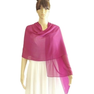 May include: A fuchsia pink chiffon shawl, draped over a white dress form. The shawl is lightweight and sheer, with a soft, flowing drape.