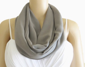 May include: A gray infinity scarf made of soft fabric. The scarf is draped around a mannequin's neck.